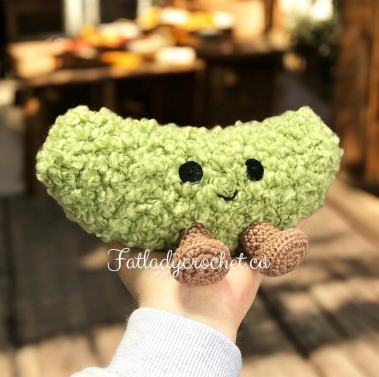 a dill pickle with a smiley face and feet being held against a kitchen backdrop.