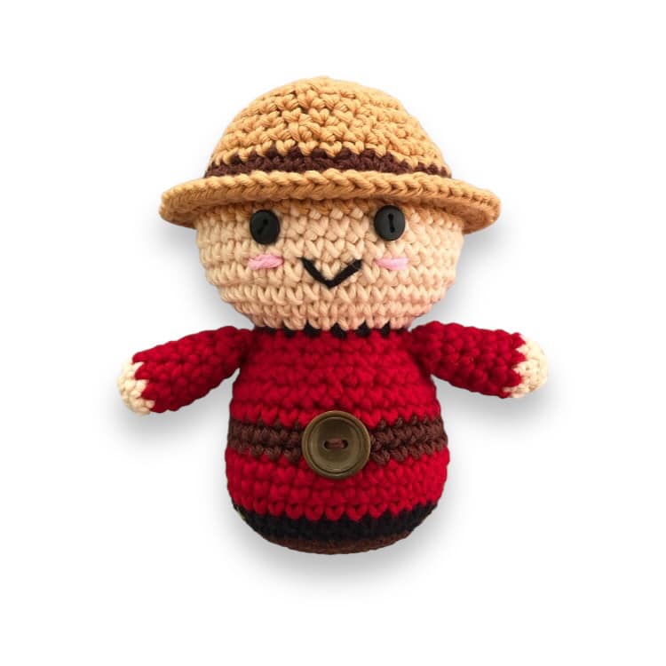 A crochet doll resembling a Canadian Mountie standing against a white background.