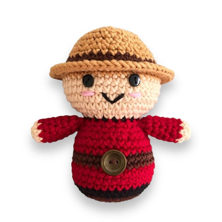 A crocheted doll resembling a Canadian Mountie standing against a white background.