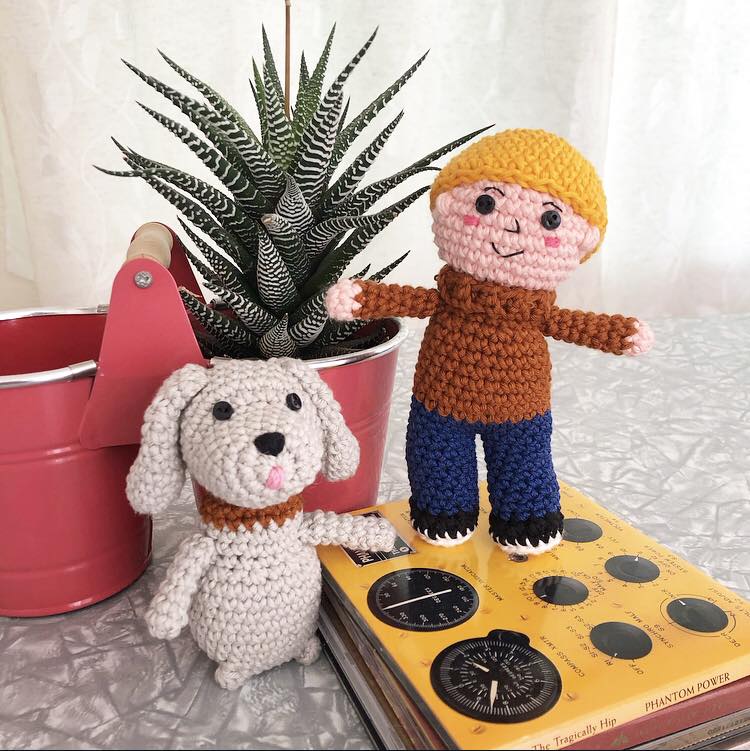 Casey and Finnegan standing together on some cd cases next to a potted plant in a small red bucket.