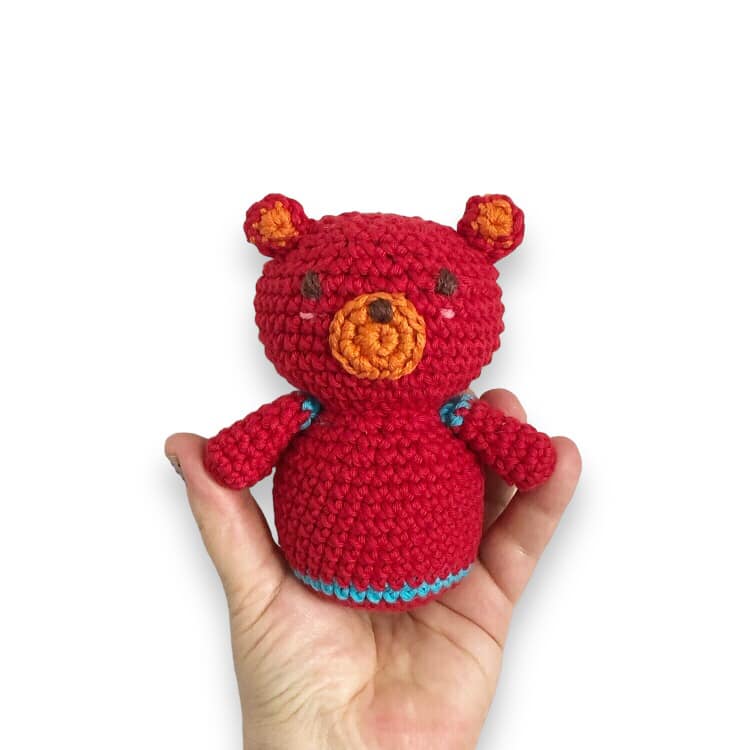 A crocheted doll resembling Boba from Cocomelon being held up against a white background.