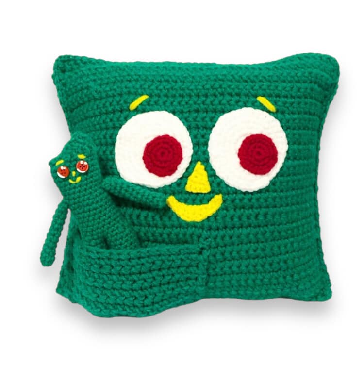 A pair of crochet Guumbys, one a pillow and the other a doll, against a white background.