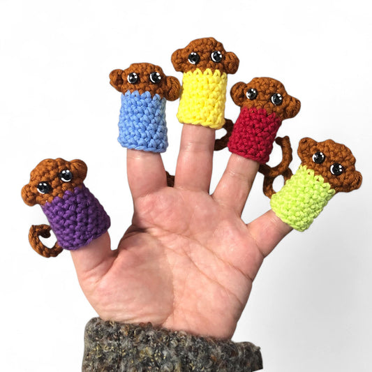 A hand displaying five little monkey finger puppets with different colored shirts in purple, yellow, blue, green, and red.