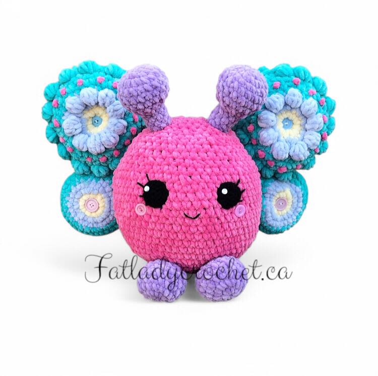 A colorful crochet pattern of a cute, round creature with butterfly wings and flower patterns, in shades of pink, turquoise, and lilac.
