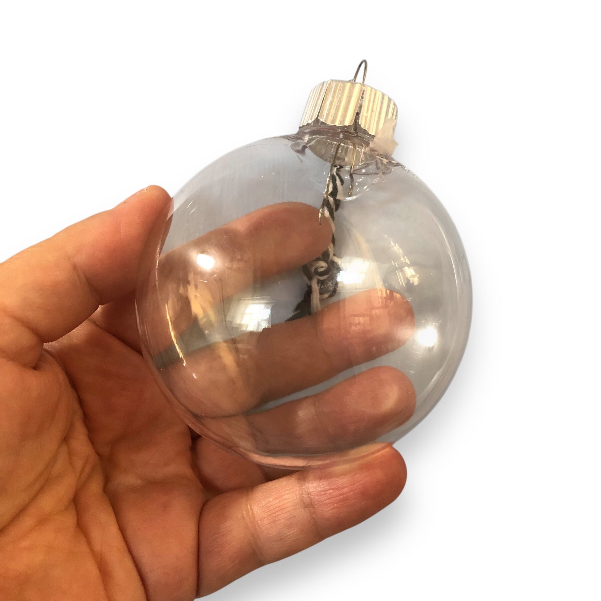 Clear plastic ornament held in a hand against a white background