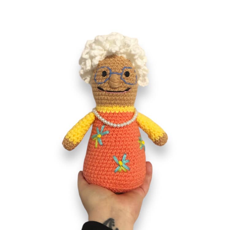 A crochet doll resembling Nana from Nana Lan being held up against a white background.