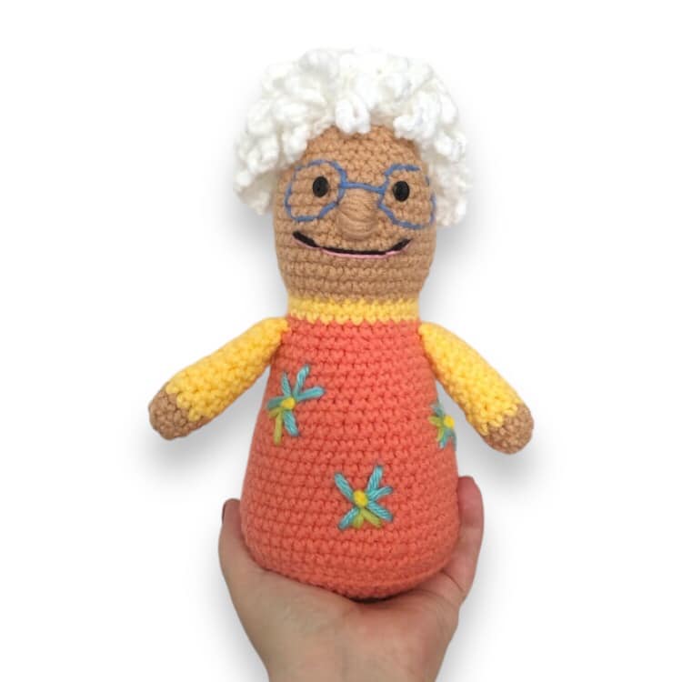 A crochet doll resembling Nana from Nana Lan being held up against a white background.