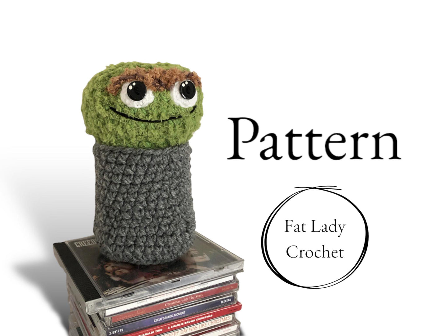 A crocheted Oscar the Grouch doll standing on CD cases against a white background with text that says "Pattern," and "Fat Lady Crochet."