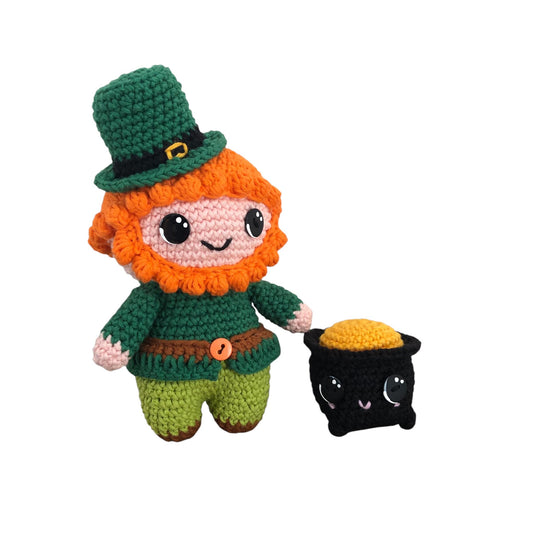 A crochet pattern depiction of a leprechaun character named Patty MacBottom, featuring green clothing, an orange beard, and a pot of gold accessory.