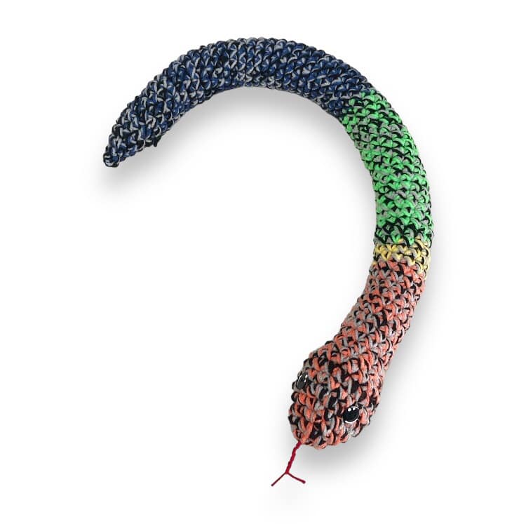 A crocheted rainbow rattle snake laid out against a white background.