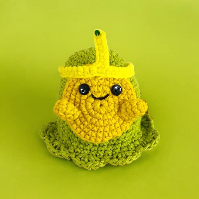 A crochet doll of Slime Princess from Adventure Time standing against a green background.