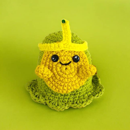 A crochet doll of Slime Princess from Adventure Time standing against a green background.