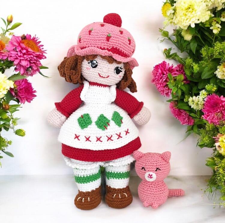 Crochet Strawberry Shortcake and Custard standing together against a white background with flowers.