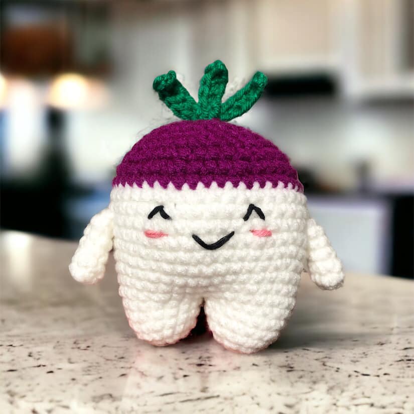 A crocheted doll resembling a cute turnip standing on a white marble kitchen counter.