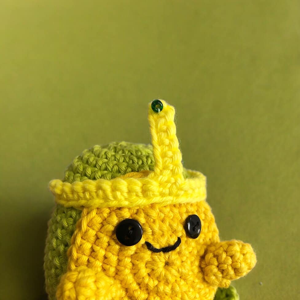 A crochet version of slime princess from adventure time standing against a white background.