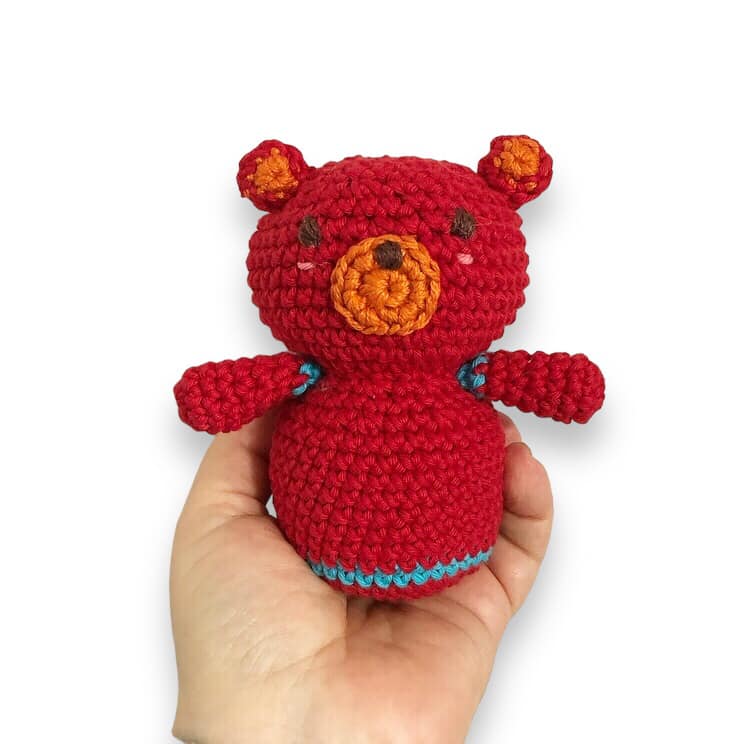 A crocheted doll resembling Boba from Cocomelon being held up against a white background.