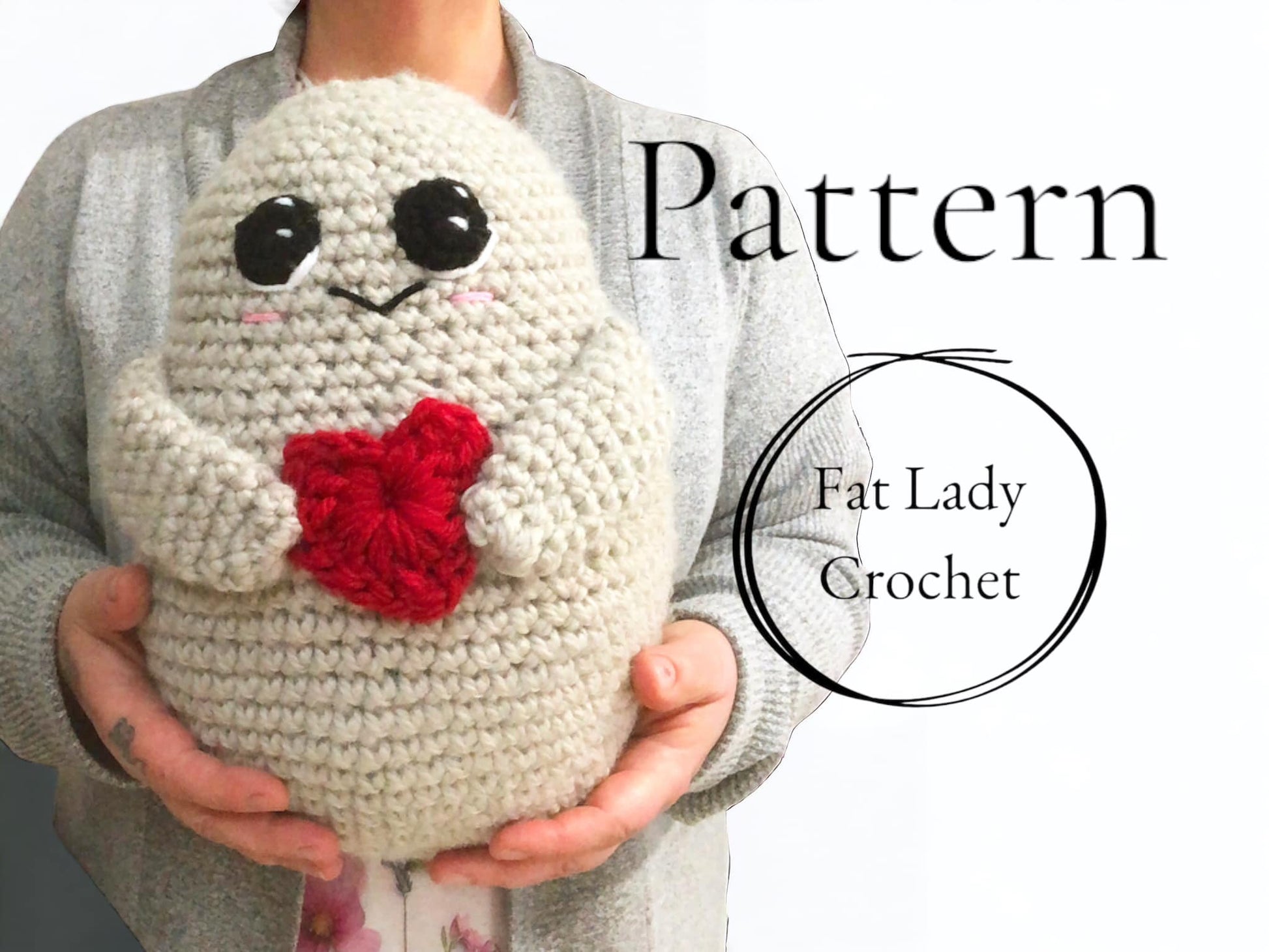 A crocheted potato with a red heart and large eyes being held up by a person with text that says "Pattern," and "Fat Lady Crochet."