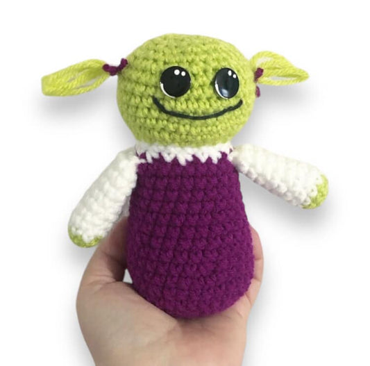 A crocheted doll of Mona from Nanalan being held up against a white background.