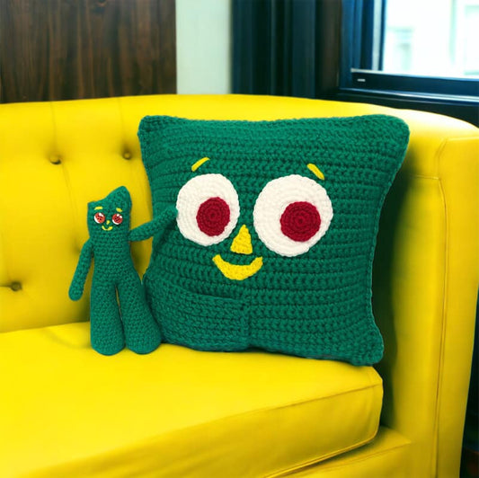 A crochet Gumby doll and Gumby pillow on a yellow couch.