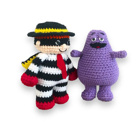 a crochet doll of Hamburglar and Grimmace standing against a white backdrop.