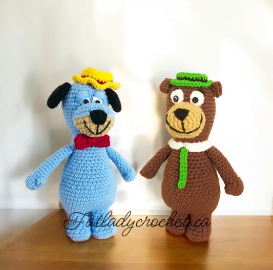 Two crochet dolls depicting cartoon characters Yogi Bear and Huckleberry Hound. Yogi is in brown color with a green scarf and Huckleberry is in blue with a red bowtie.