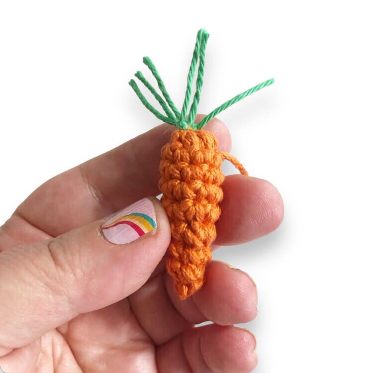 A crochet carrot piece for the Peter Rabbit crochet doll being held against a white background.