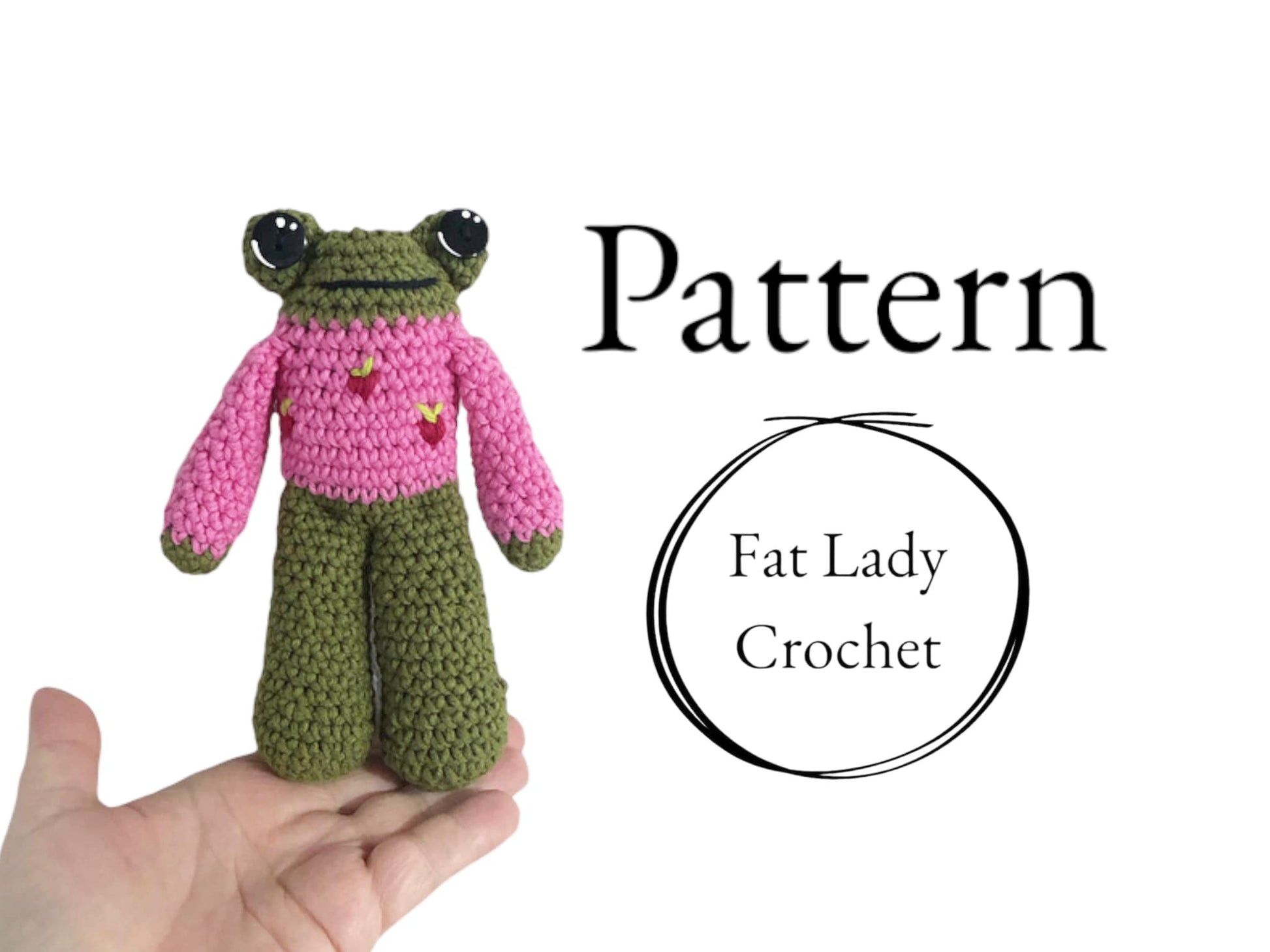 A crocheted frog doll in a pink sweater with strawberries being held up against a white background with text that reads "Pattern," and "Fat Lady Crochet."