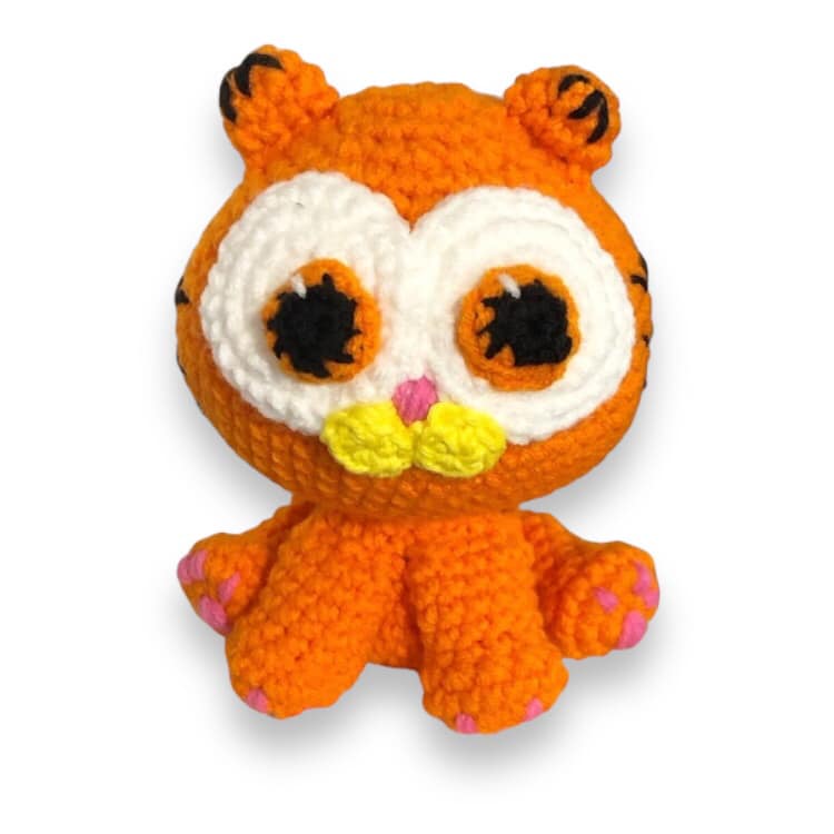 A crochet plush resembling Garfield as a kitten against a white background. 