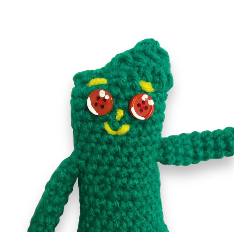 A close up of a crocheted Gumby doll. 