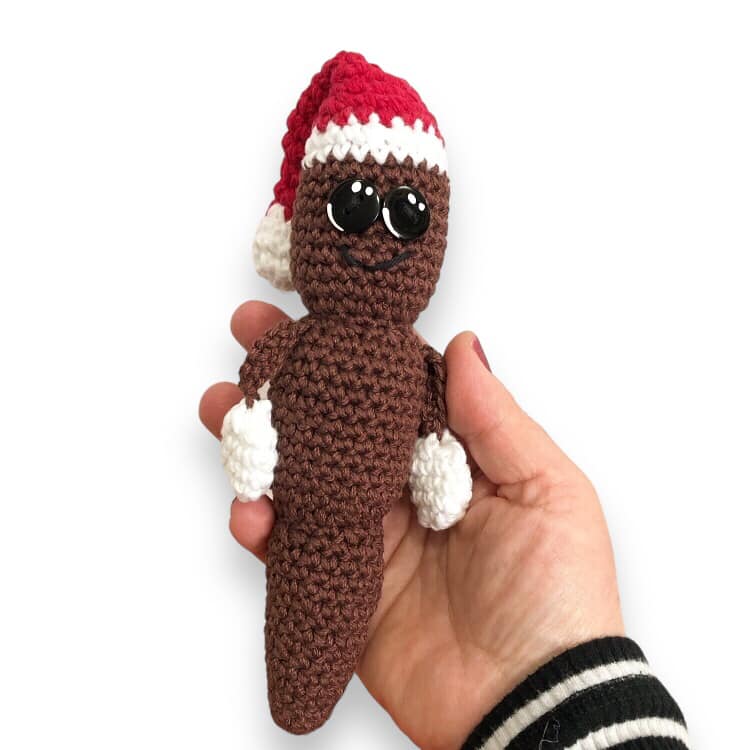 A crochet doll resembling Mr. Hanky the Christmas Poo being held up against a white background.