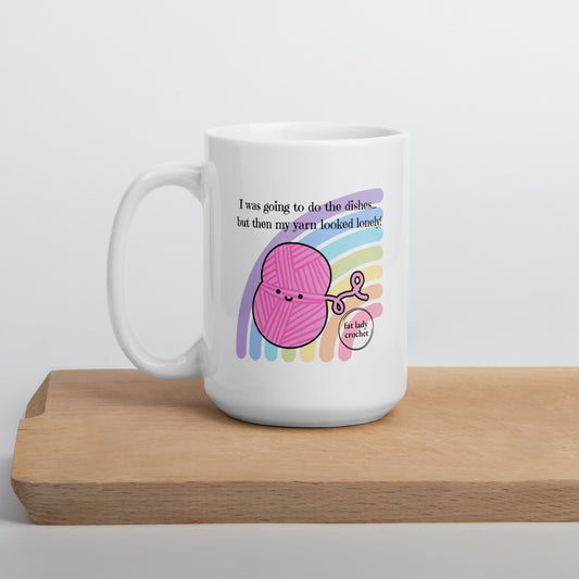 White porcelain mug with pink yarn that has a smiley face against a pastel rainbow. 