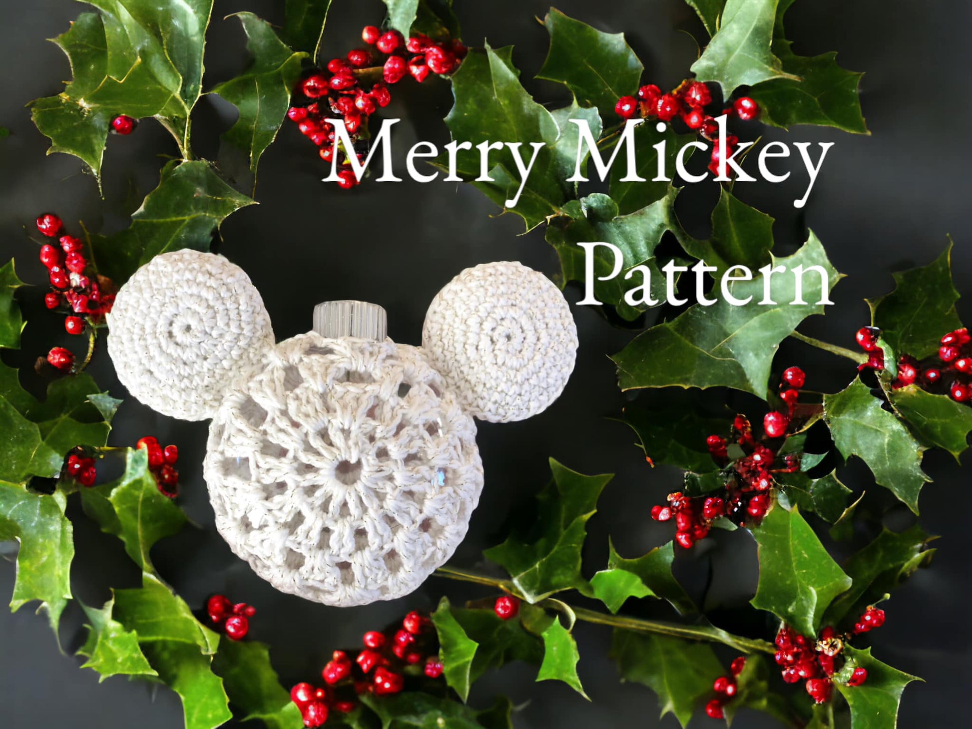 A crocheted white Mickey Mouse ornament surrounded by Holly with text that reads "Merry Mickey Pattern." 