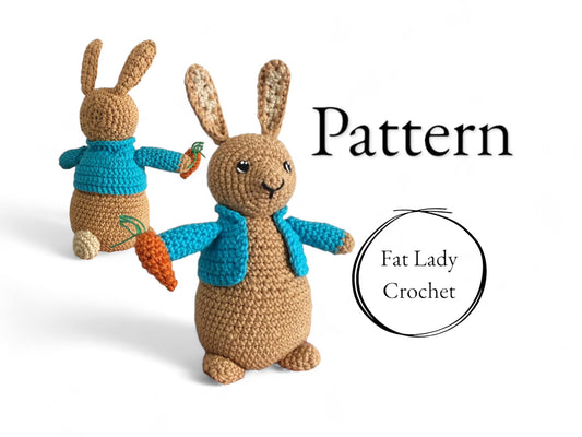 A crochet Peter Rabbit doll standing against a white background and holding a carrot with a blue coat with text saying "Pattern," and "Fat Lady Crochet." 