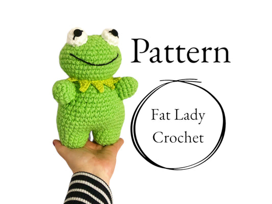 A crocheted doll resembling Kermit the Frog being held up against a white background with text that reads "Pattern.," and "Fat Lady Crochet." 