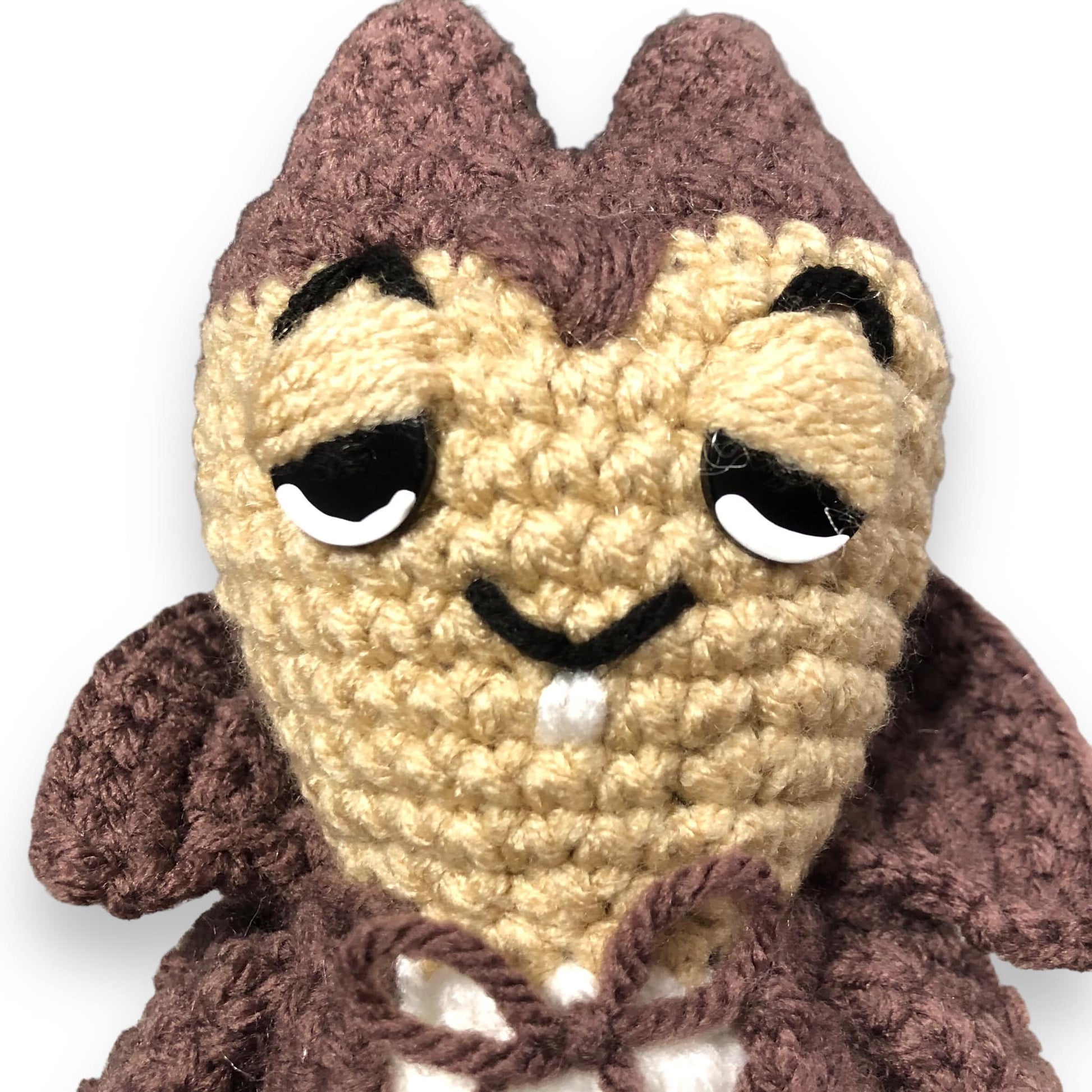 Not gonna lie, this man looks high, but good for him I guess. Slay. Anyway, a close up of the crochet Count Count Chocula doll's face against a white background. 