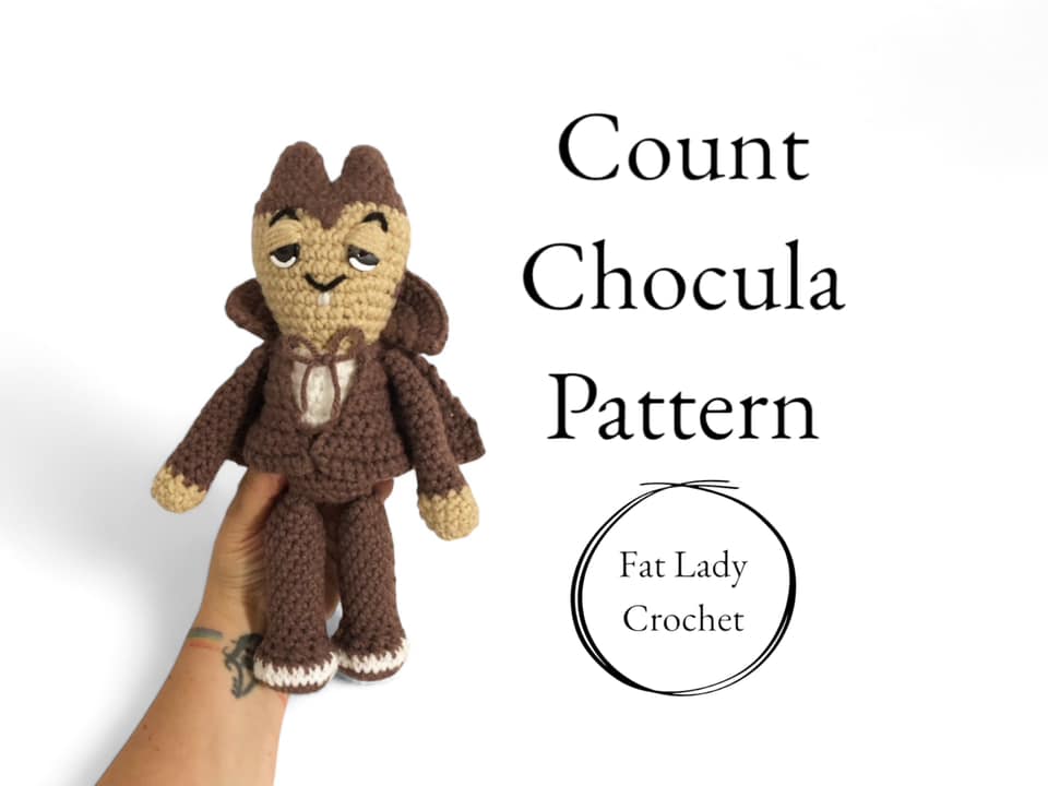 A crochet doll of Count Chocula being held up against a white background with text that reads "Count Chocula Pattern," and "Fat Lady Crochet." 