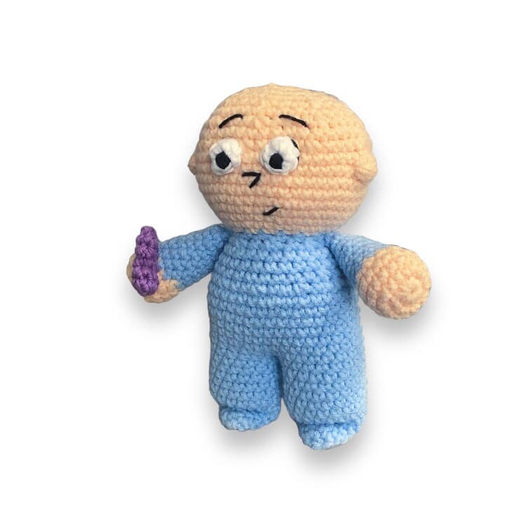 A crocheted doll resembling Harold from Harold and the Purple Crayon being standing against a white background. 
