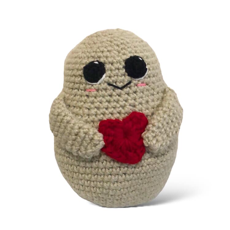 A large crochet potato with a red heart standing against a white background. 