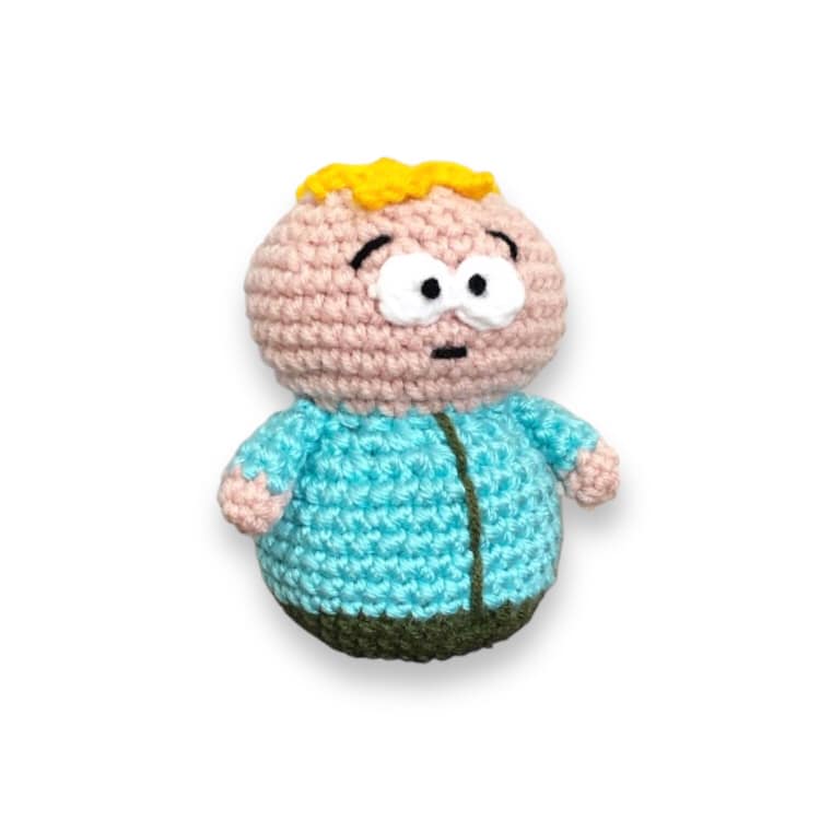 A crochet doll resembling Butters from South Park standing against a white background. 