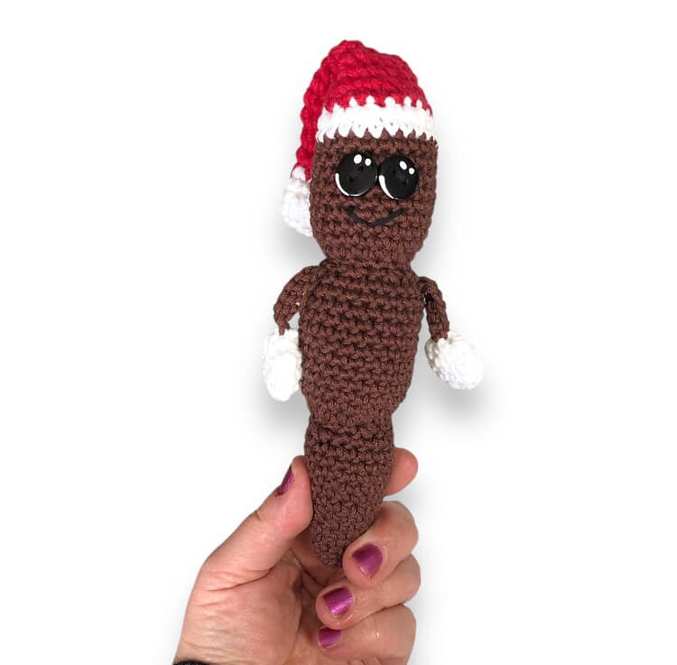 A crochet doll resembling Mr. Hanky the Christmas Poo being held up against a white background.